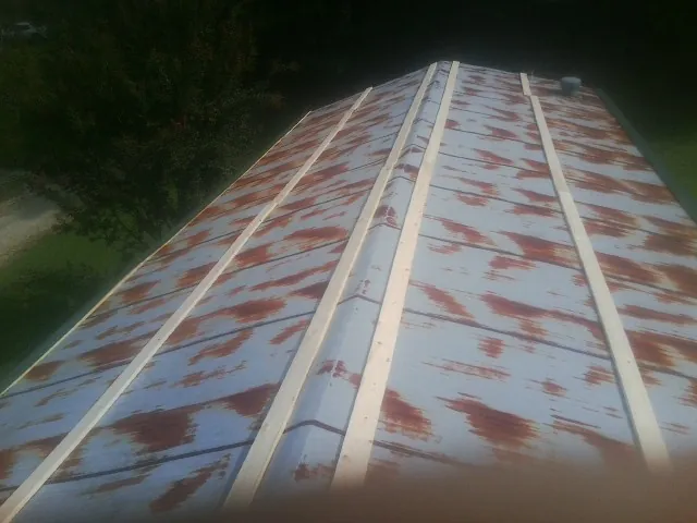 Rusted metal roof panels with new wood purlins before replacement — Storm Damage Roof Repair in West Greenwich by Roofing Brothers