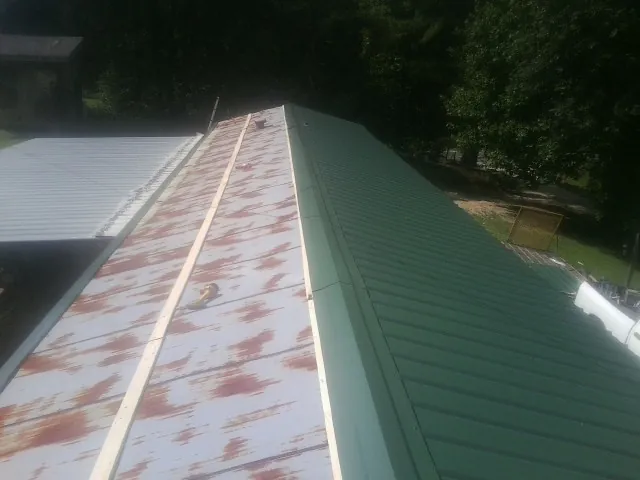 Old rusted panels beside newly installed green metal roofing — Wind Damage Roof Repair by Roofing Brothers in West Greenwich