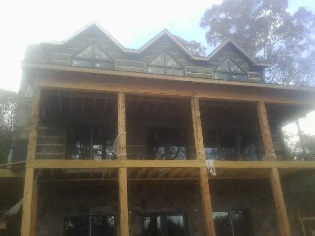 Dormers and porch framing on a large log home under construction — Roof Coating work by our crew in West Greenwich