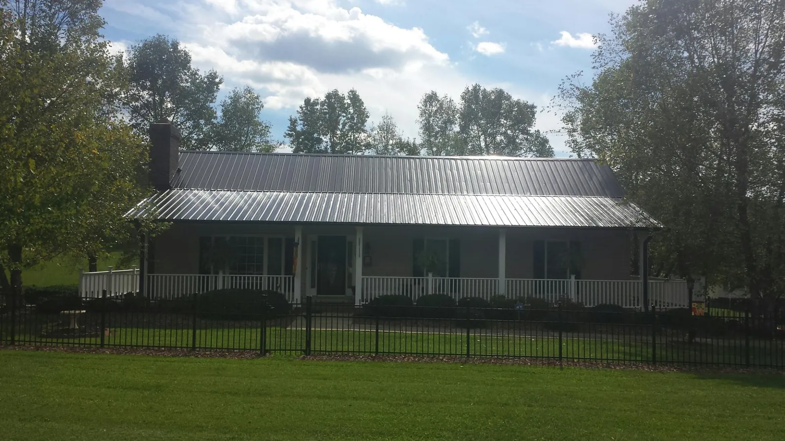 Gray metal roof on a brick ranch with a full width front porch — Gutter Guard Installation work by our crew in West Greenwich