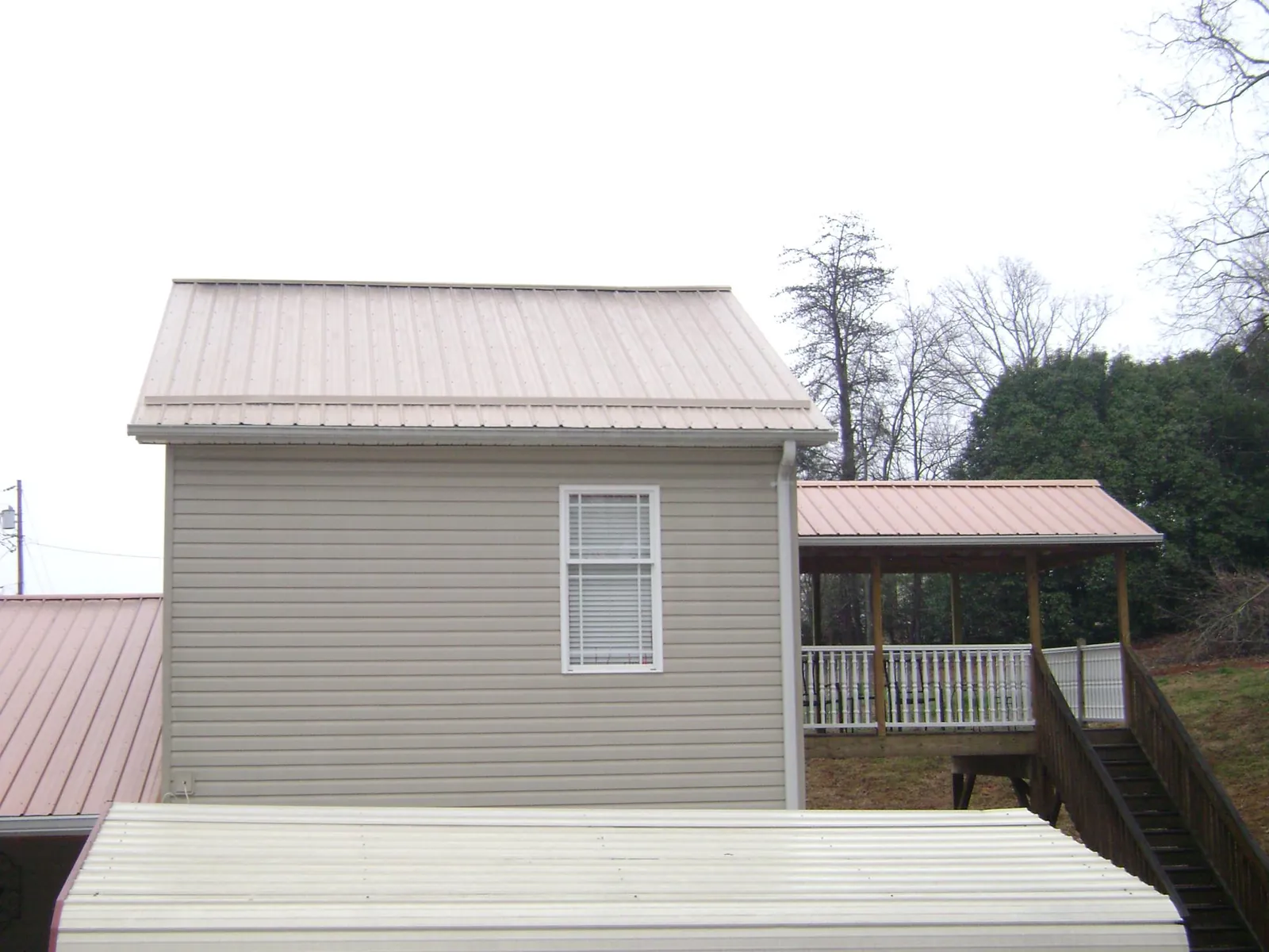 Tan metal roofs on a two story addition and attached porch, from a Roof Replacement job in West Greenwich