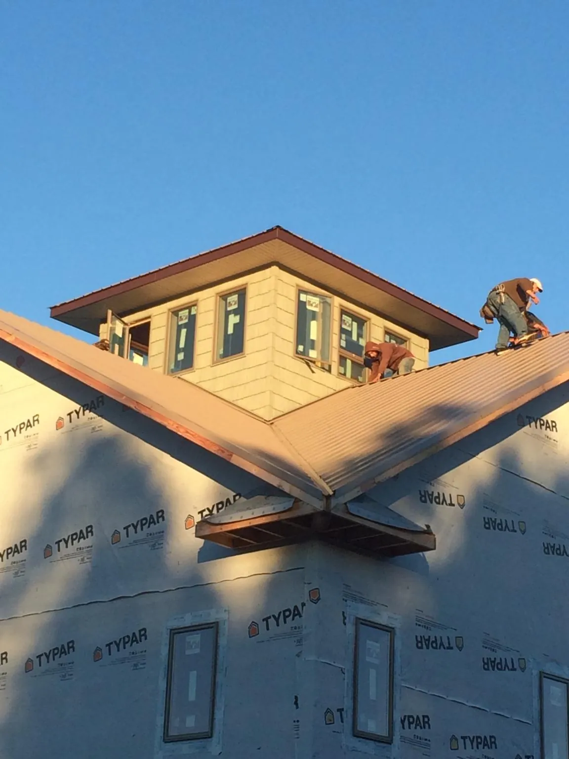 Roofers working around a rooftop cupola on a new metal roof at sunset — Roof Waterproofing in West Greenwich by Roofing Brothers